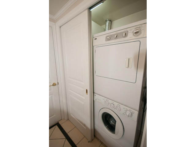Bright laundry room with stacked washer and dryer, white cabinetry. - 1122 Ironwork Passage, Vancouver West Side