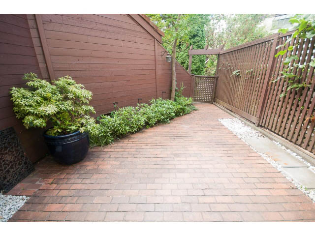 Furnished patio with brick paving and wooden fencing, surrounded by greenery. - 1122 Ironwork Passage, Vancouver West Side