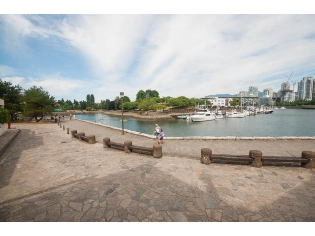 Furnished patio with stone flooring, waterfront view, and docked boats. - 1122 Ironwork Passage, Vancouver West Side