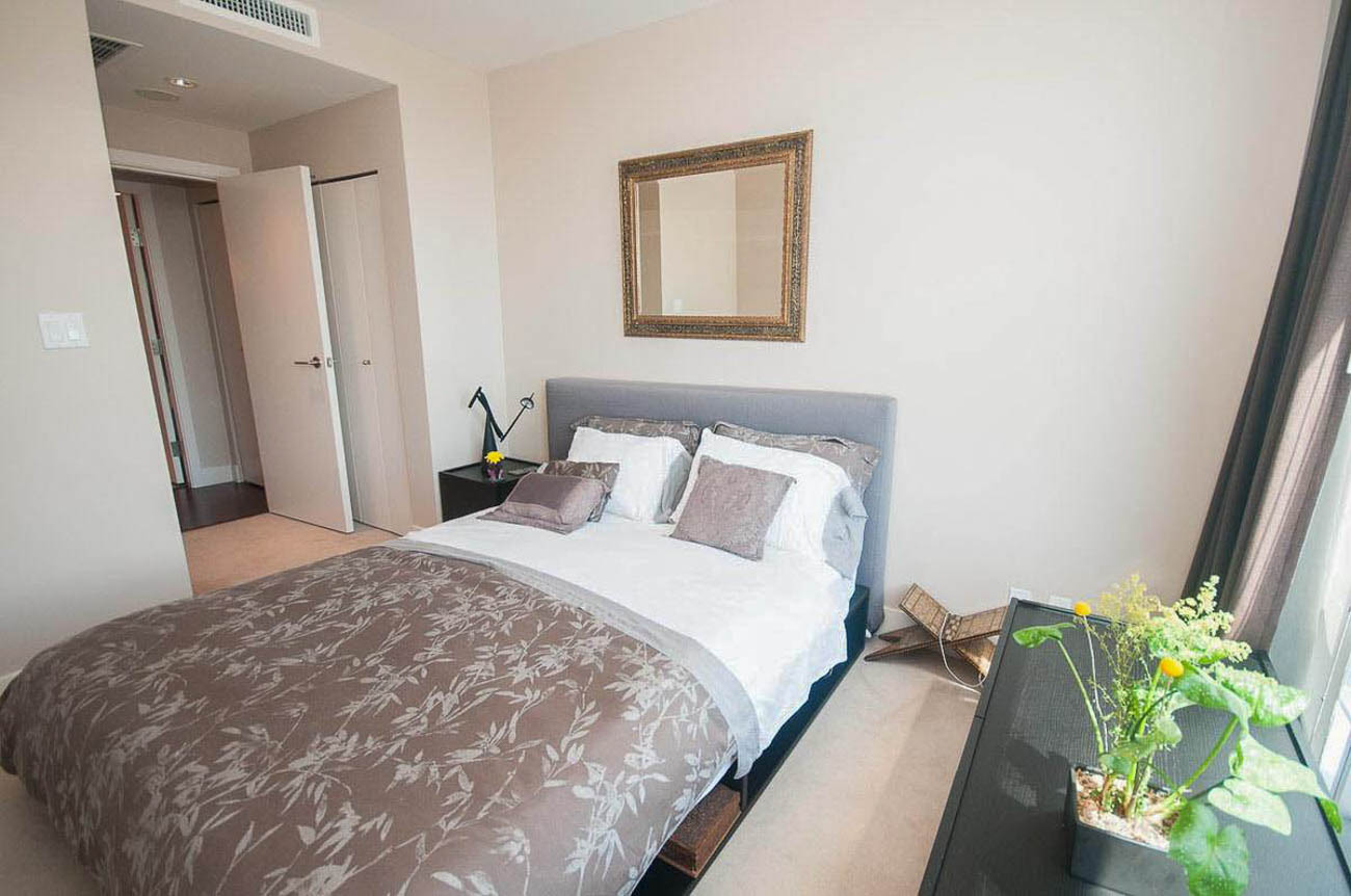Furnished 1-bedroom with a cozy bed, neutral walls, and a small bedside table. - 2806 - 1111 Alberni Street, Vancouver Downtown