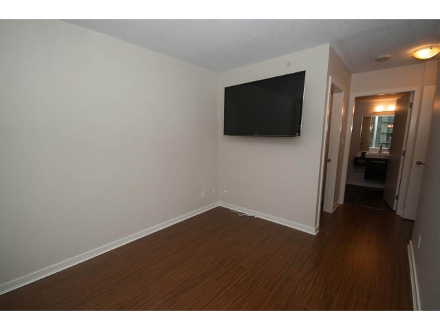 Living room with hardwood floors and a mounted TV. - 605 - 633 Abbott St, Vancouver Downtown