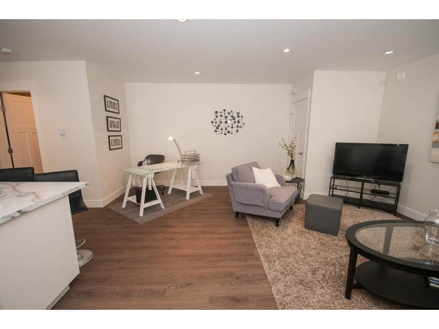 Bright living room with hardwood floors, modern decor, and a cozy corner setup. - Suite - 4638 Strathcona Rd, North Vancouver