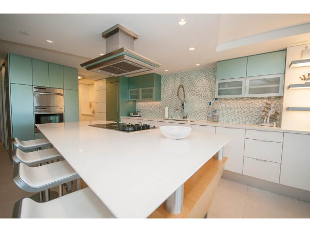 Bright kitchen with white countertops, light green cabinets, and a modern vent hood. - 708 - 27 Alexander St, Vancouver Downtown