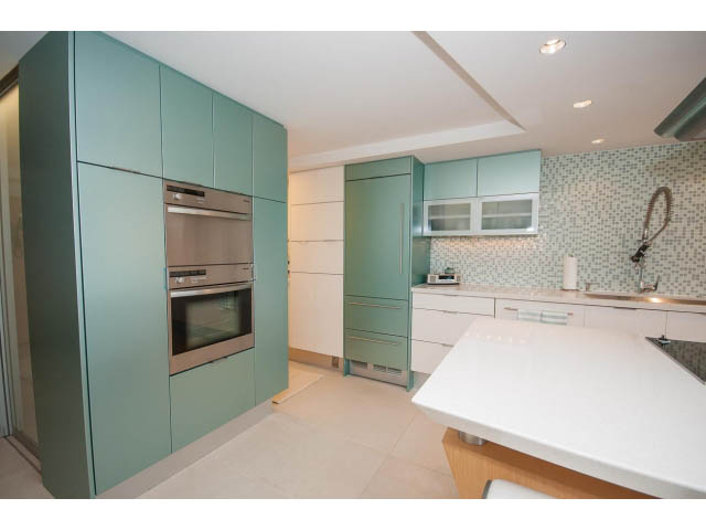 Bright kitchen with white countertops, teal cabinets, and modern appliances. - 708 - 27 Alexander St, Vancouver Downtown