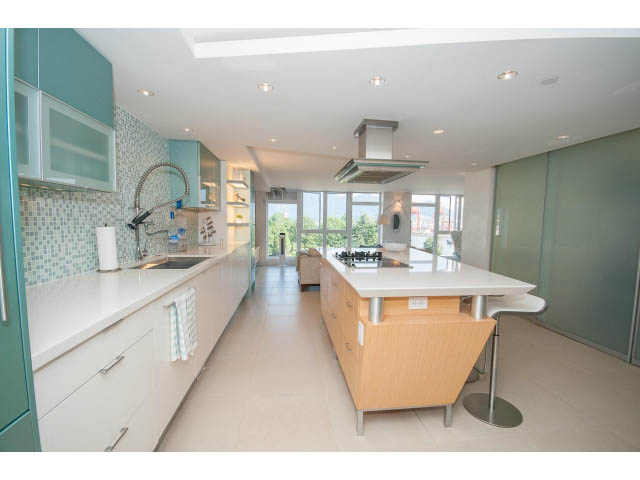 Bright kitchen with light wood cabinets, white countertops, and a city view. - 708 - 27 Alexander St, Vancouver Downtown
