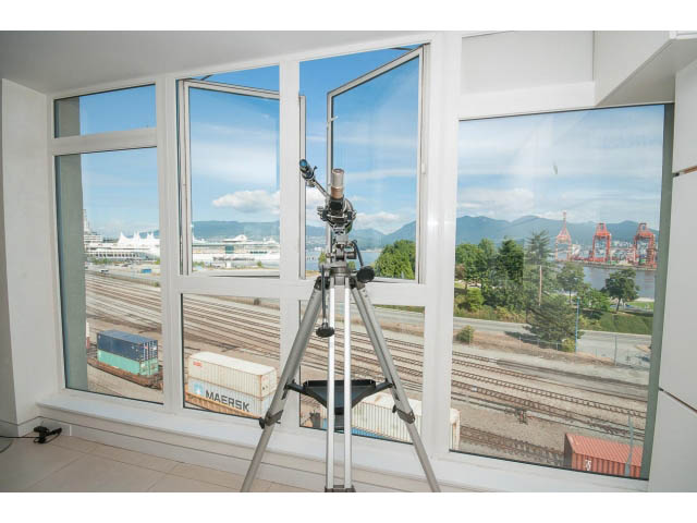 Bright living room with large bay window offering a stunning city view and train yard scene. - 708 - 27 Alexander St, Vancouver Downtown