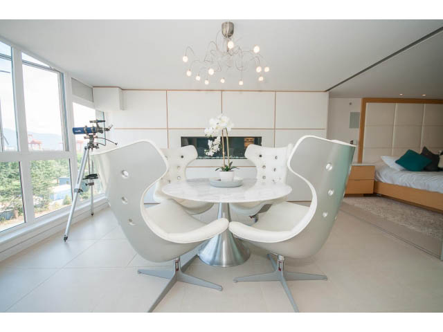 Bright dining area with modern white chairs and a sleek table, city view through large windows. - 708 - 27 Alexander St, Vancouver Downtown