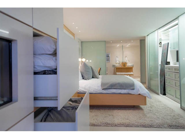 Bright and modern 1-bedroom condo with sleek white cabinetry, cozy bedding, and a spacious bathroom with a glass shower.