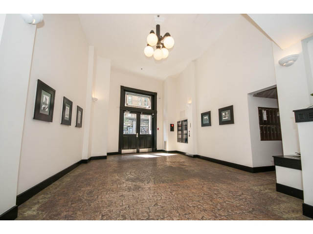 Spacious living room with white walls, framed artwork, and a chandelier. - 708 - 27 Alexander St, Vancouver Downtown
