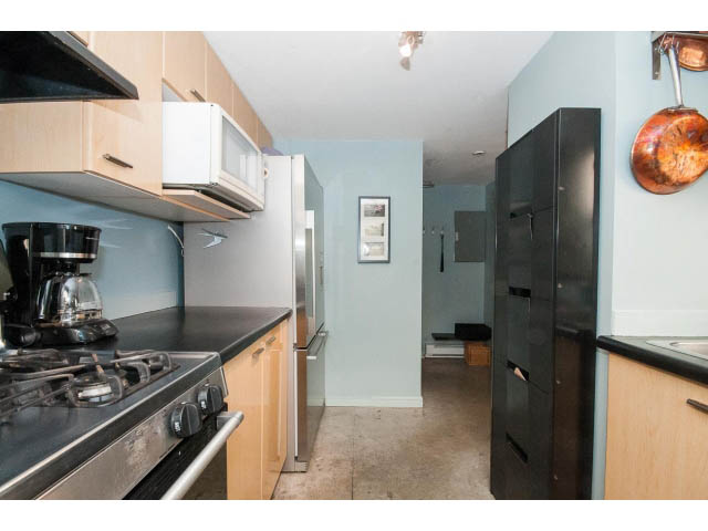 Bright kitchen with stainless steel appliances, light wood cabinets, and a view of the living area. - 716 - 428 West 8th Ave, Vancouver West Side