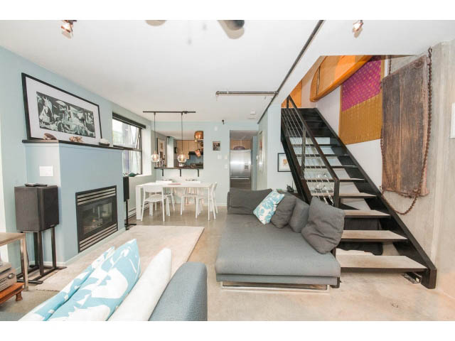 Furnished living room with modern furniture, exposed brick, and a staircase leading to the upper level. - 716 - 428 West 8th Ave, Vancouver West Side