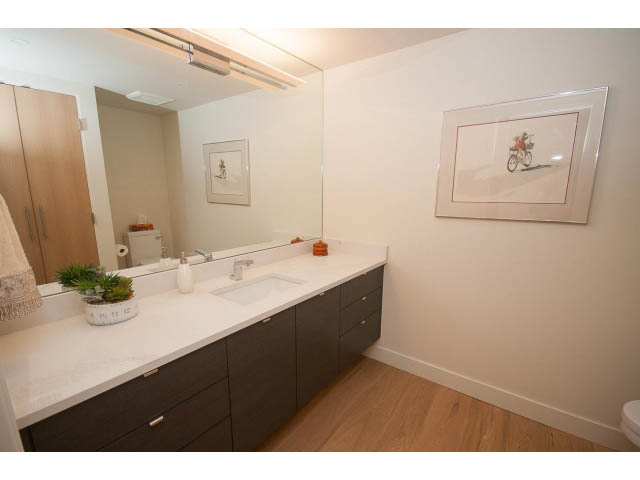 Spacious bathroom with white countertops, wooden floors, and a large mirror. - 103 - 1860 Robson Street, Vancouver Downtown
