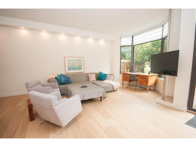 Spacious living room with hardwood floors, modern furniture, and a large window. - 103 - 1860 Robson Street, Vancouver Downtown