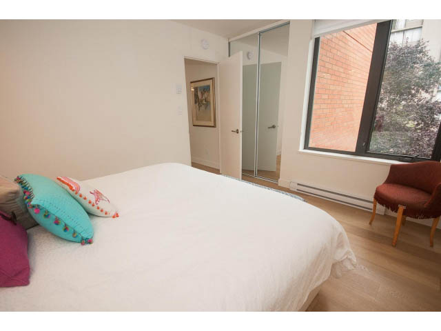 Bright bedroom with hardwood floors, large window, and cozy bedding. - 103 - 1860 Robson Street, Vancouver Downtown