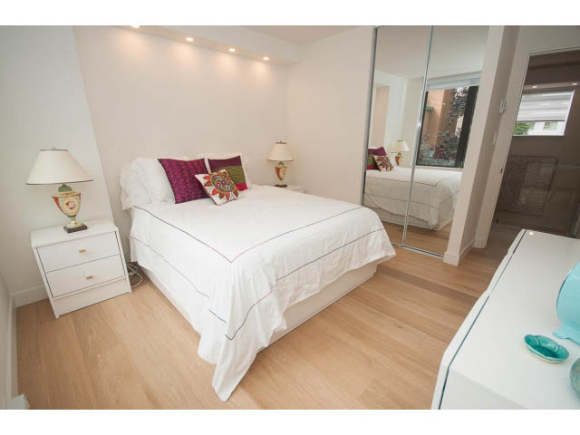 Bright bedroom with hardwood floors, white furniture, and a large mirror. - 103 - 1860 Robson Street, Vancouver Downtown