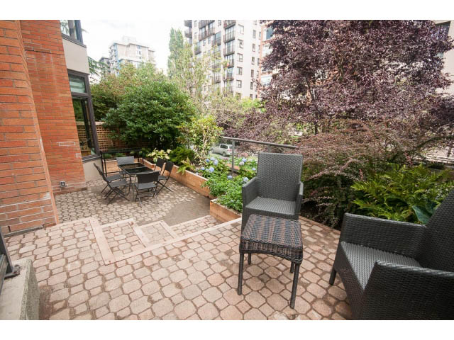 Furnished patio with outdoor seating and greenery, brick wall backdrop. - 103 - 1860 Robson Street, Vancouver Downtown