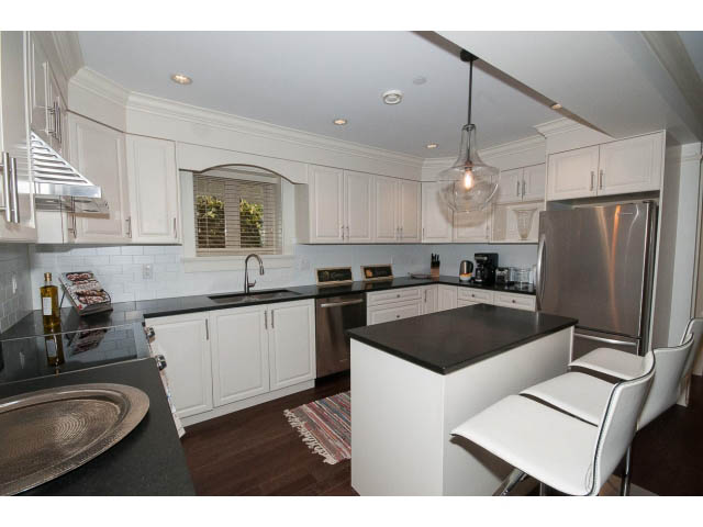Bright kitchen with white cabinets, stainless steel appliances, and dark countertops. - 1836 Greer Ave, Vancouver West Side