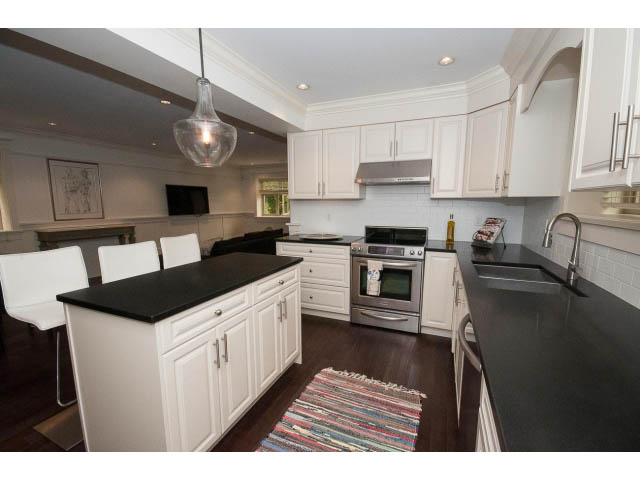 Bright kitchen with black countertops, white cabinets, and hardwood floors. - 1836 Greer Ave, Vancouver West Side