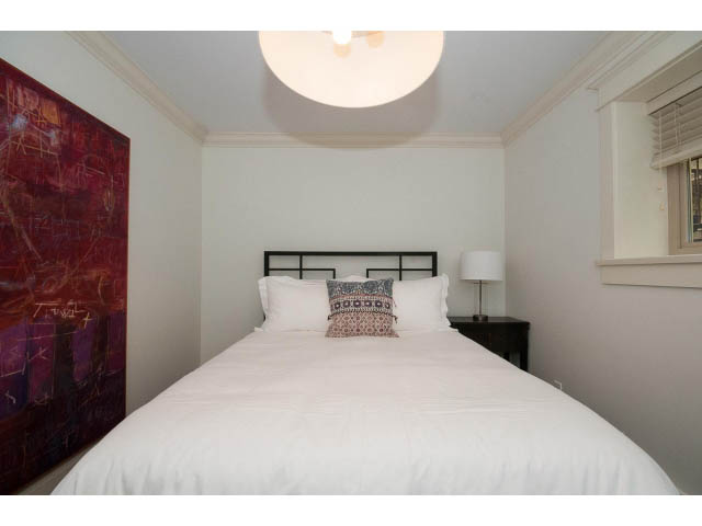 Bright bedroom with white bedding, abstract art, and modern decor. - 1836 Greer Ave, Vancouver West Side