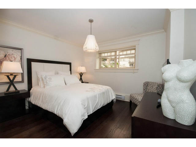 Spacious bedroom with hardwood floors, white bedding, and a window view. - 1836 Greer Ave, Vancouver West Side