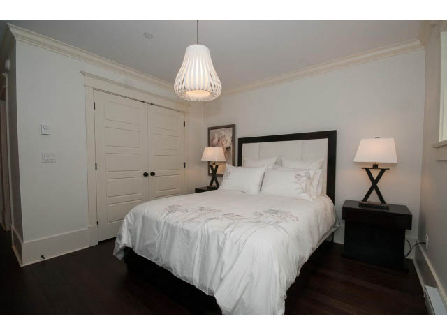 Bright bedroom with white walls, dark hardwood floors, and a modern pendant light. - 1836 Greer Ave, Vancouver West Side