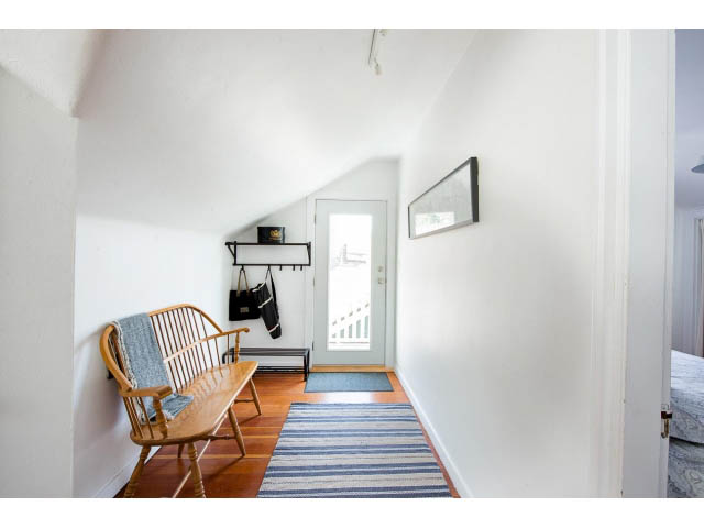 Bright entryway with wooden bench, striped rug, and white walls. - Upper - 732 East 9th St, North Vancouver
