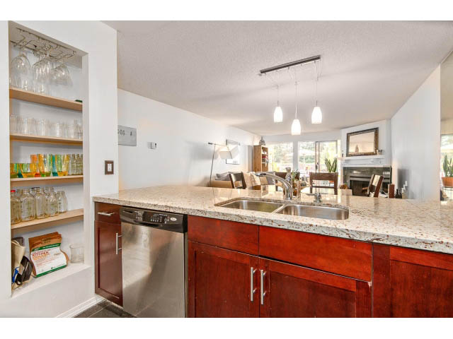 Bright kitchen with granite countertops, wooden cabinets, and pendant lighting. - 101 - 2288 Laurel st., Vancouver West Side