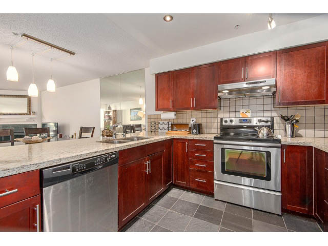 Bright kitchen with granite countertops, stainless steel appliances, and dark wood cabinets. - 101 - 2288 Laurel st., Vancouver West Side
