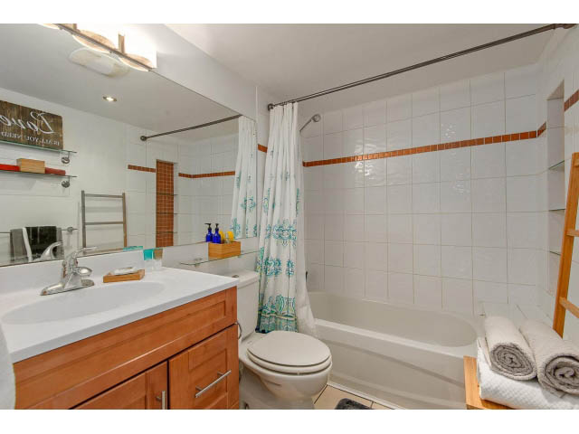 Furnished bathroom with white countertops, wooden cabinets, and a bathtub/shower combo. - 101 - 2288 Laurel st., Vancouver West Side