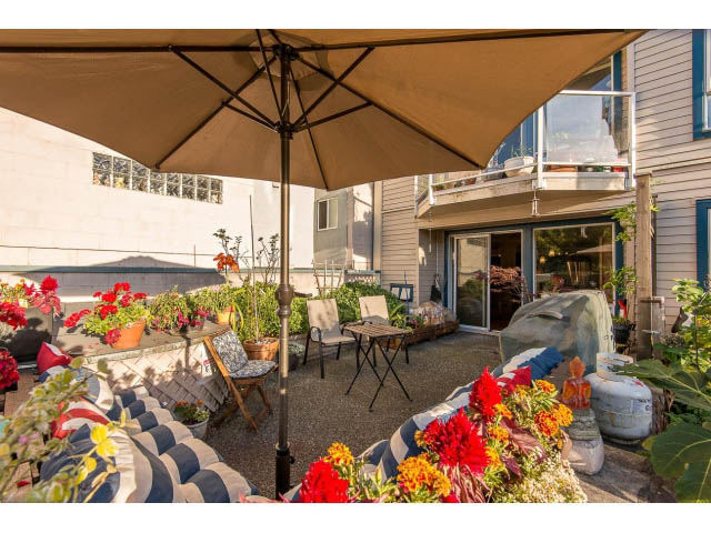 Furnished patio with umbrella, flowers, and outdoor furniture. - 101 - 2288 Laurel st., Vancouver West Side