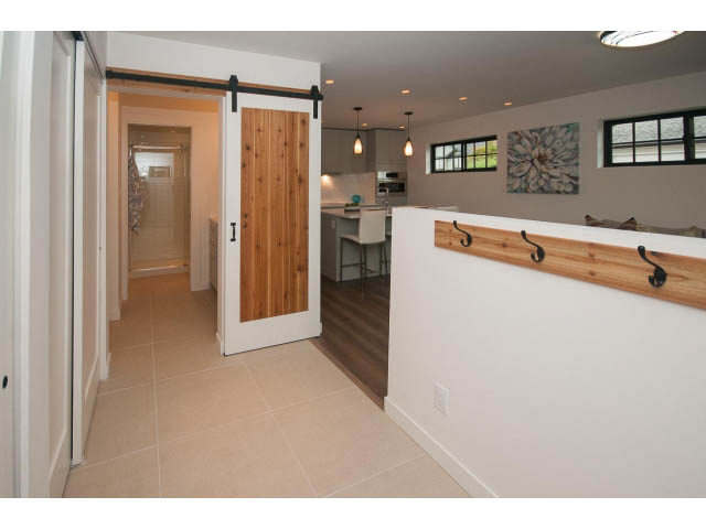 Bright kitchen with white cabinets, wood accents, and sliding barn door. - 840-3 E 16th St., North Vancouver