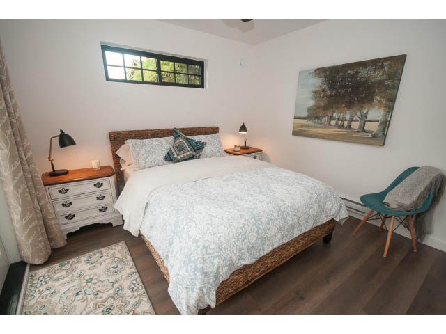 Cozy 1-bedroom furnished bedroom with hardwood floors, a wicker bed, and a scenic painting. - 840-3 E 16th St., North Vancouver