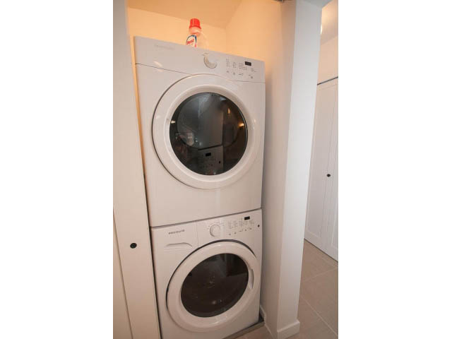 Laundry room with stacked washer and dryer, white cabinets. - 840-3 E 16th St., North Vancouver