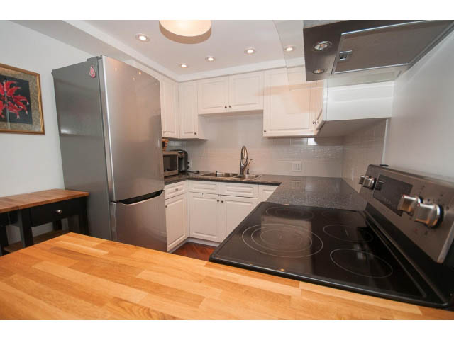 Bright kitchen with stainless steel appliances, wooden countertops, and white cabinets. - 1204 - 1625 Hornby St, Vancouver Downtown