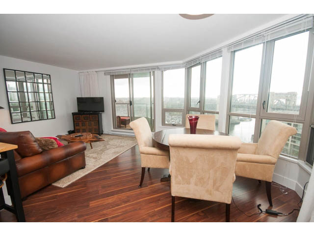 Spacious living room with hardwood floors, large windows, and a city view. - 1204 - 1625 Hornby St, Vancouver Downtown