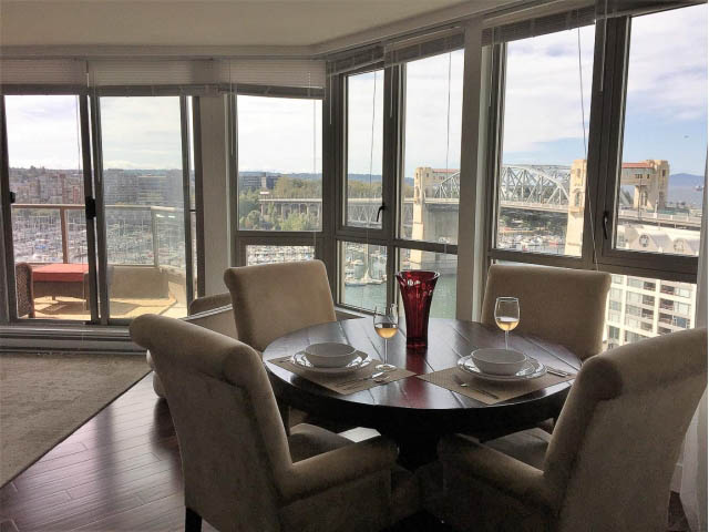 Dining area with a view of the city and bridge, featuring a round table and modern chairs. - 1204 - 1625 Hornby St, Vancouver Downtown