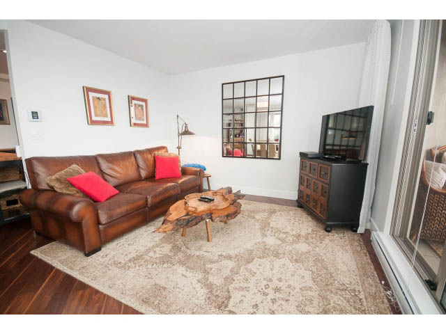 Furnished living room with leather couch, hardwood floors, and a city view. - 1204 - 1625 Hornby St, Vancouver Downtown