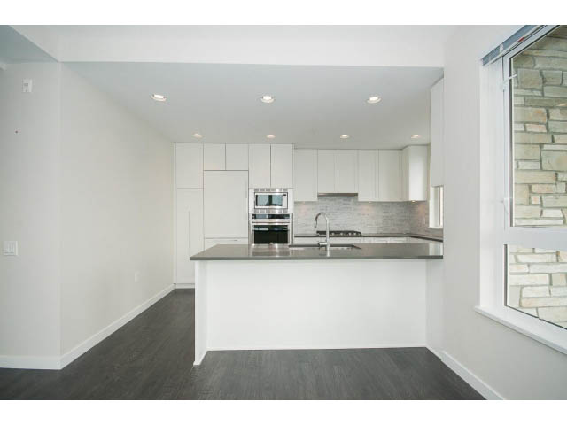 Bright kitchen with white cabinetry, hardwood floors, and a stone backsplash. - 303 - 3825 Cate's Landing, North Vancouver