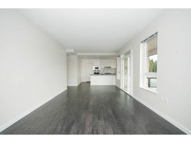 Bright open-concept living space with hardwood floors and modern kitchen counter. - 303 - 3825 Cate's Landing, North Vancouver