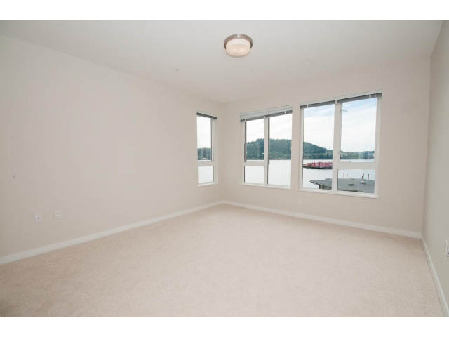 Bright living room with large windows and a city view. - 303 - 3825 Cate's Landing, North Vancouver