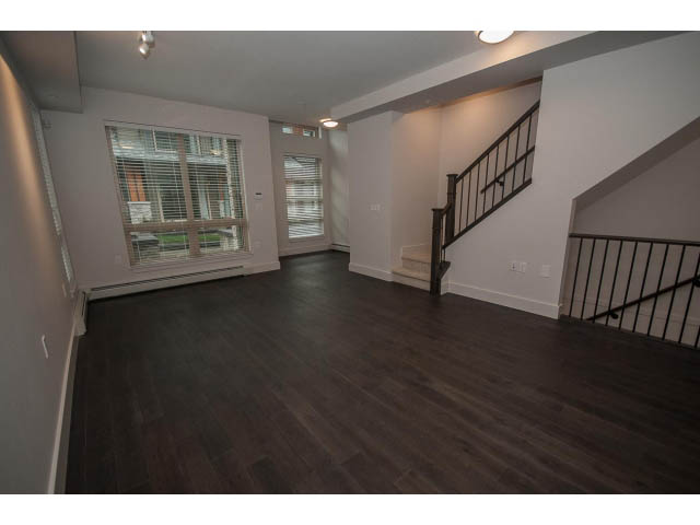 Spacious living room with hardwood floors and a staircase leading to the upper level. - 5 - 244 5th E St, North Vancouver