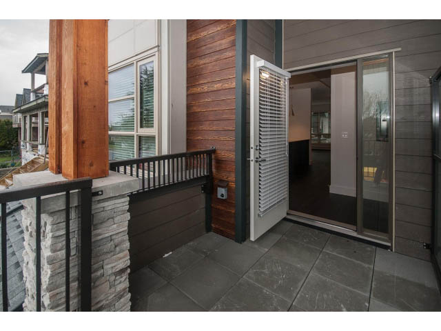 Furnished balcony with modern railings and sliding glass doors leading to a cozy interior. - 5 - 244 5th E St, North Vancouver