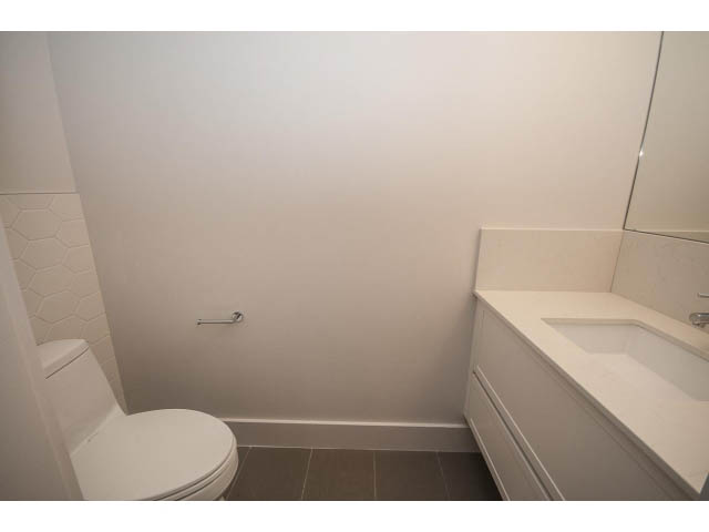 Bathroom with white countertop and hexagonal tile backsplash. - 5 - 244 5th E St, North Vancouver