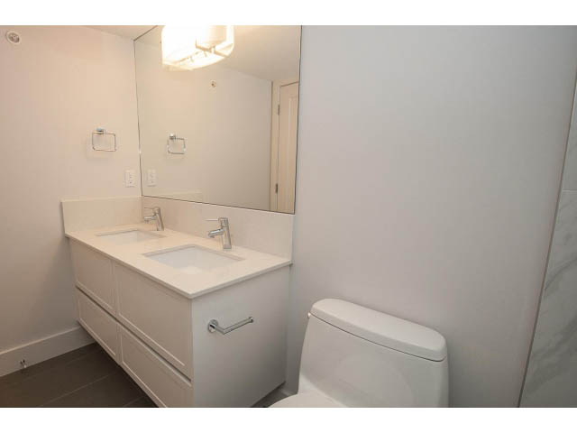 Bright bathroom with white vanity and toilet, modern light fixture. - 5 - 244 5th E St, North Vancouver