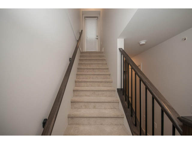 Staircase leading to upper level with wooden railings and carpeted steps. - 5 - 244 5th E St, North Vancouver