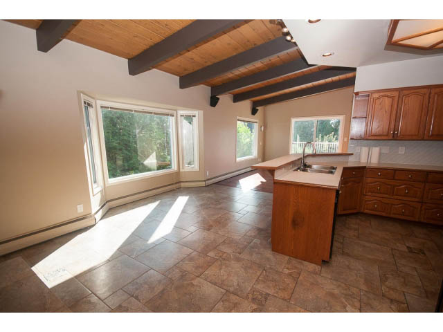 Bright kitchen with wooden cabinets, granite countertops, and large windows offering a city view. - 4135 Golf drive, North Vancouver