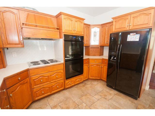 Bright kitchen with light wood cabinets, black appliances, and tiled floor. - 4135 Golf drive, North Vancouver