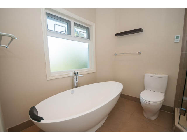 Bright bathroom with modern freestanding bathtub and frosted glass window. - 4135 Golf drive, North Vancouver