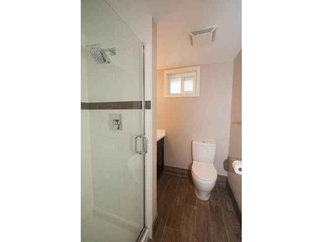 Bright bathroom with glass shower, wooden floors, and a small window. - 4135 Golf drive, North Vancouver