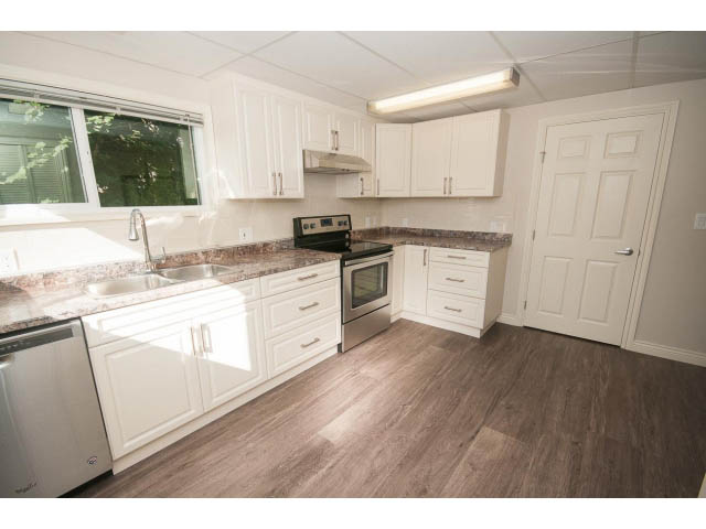 Bright kitchen with white cabinets, granite countertops, and hardwood floors. - 4135 Golf drive, North Vancouver